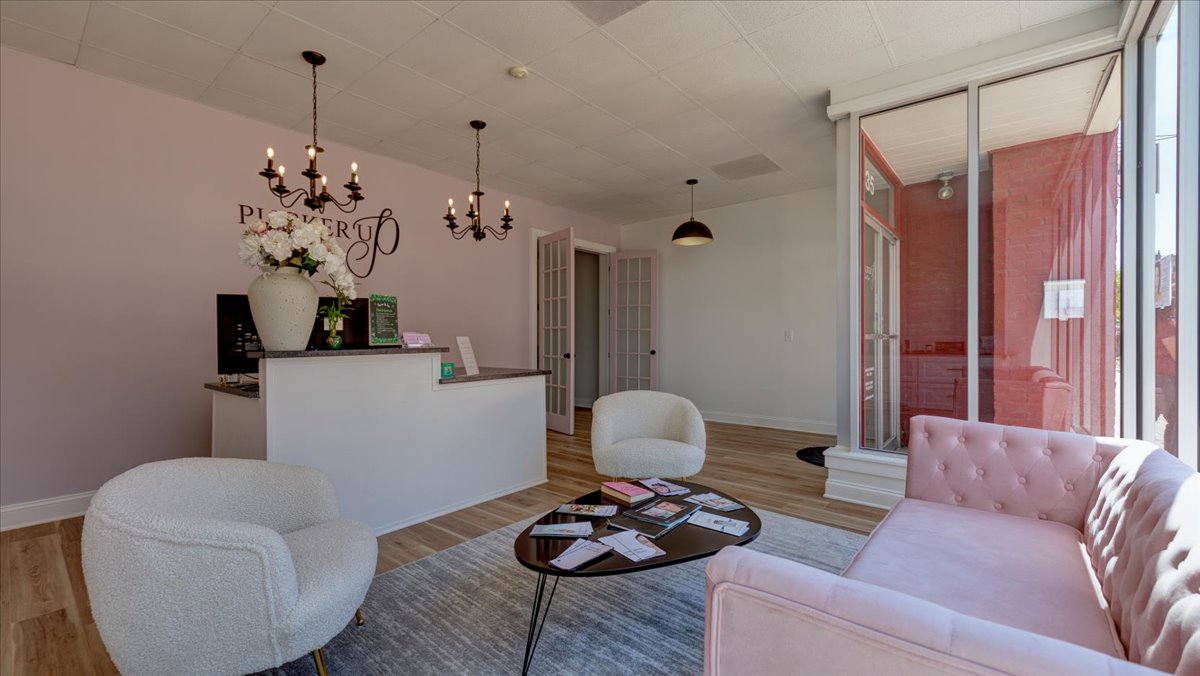 A dental office waiting room with light pink walls and chandeliers.