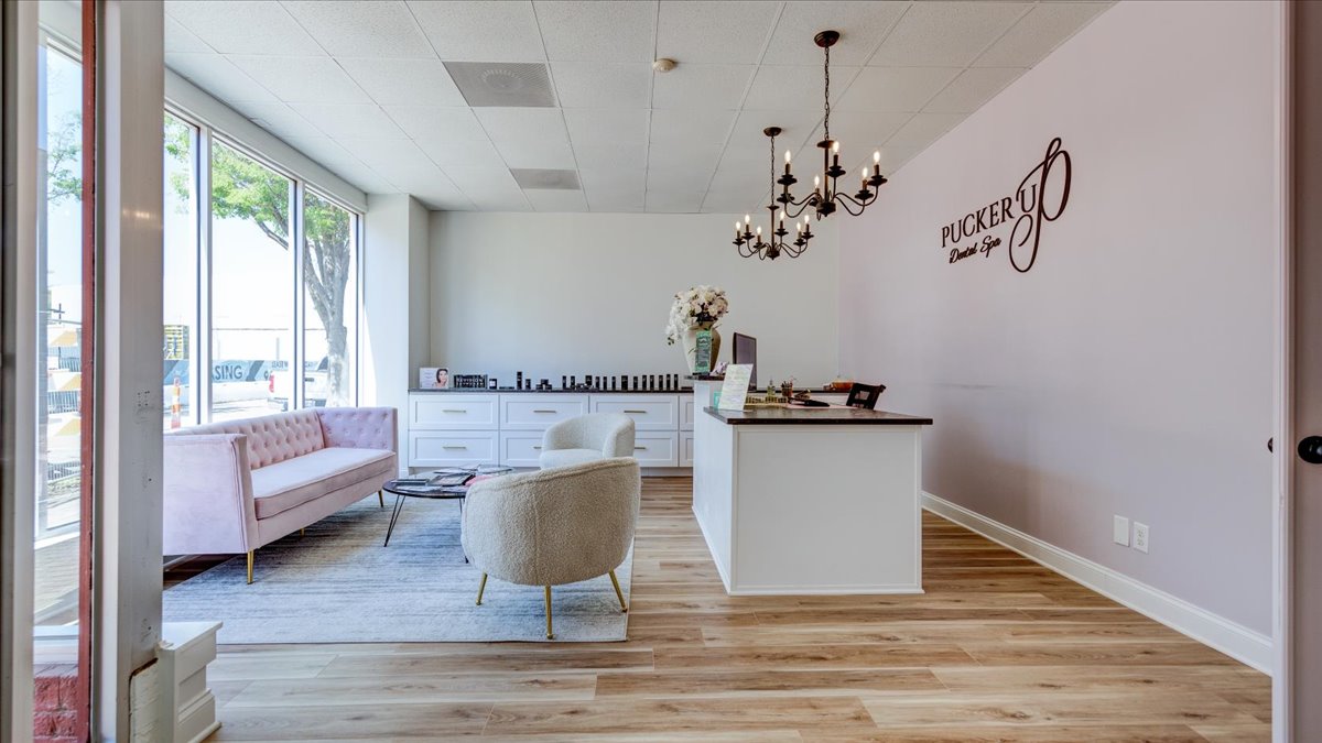 A dental office waiting room with light pink walls and chandeliers.