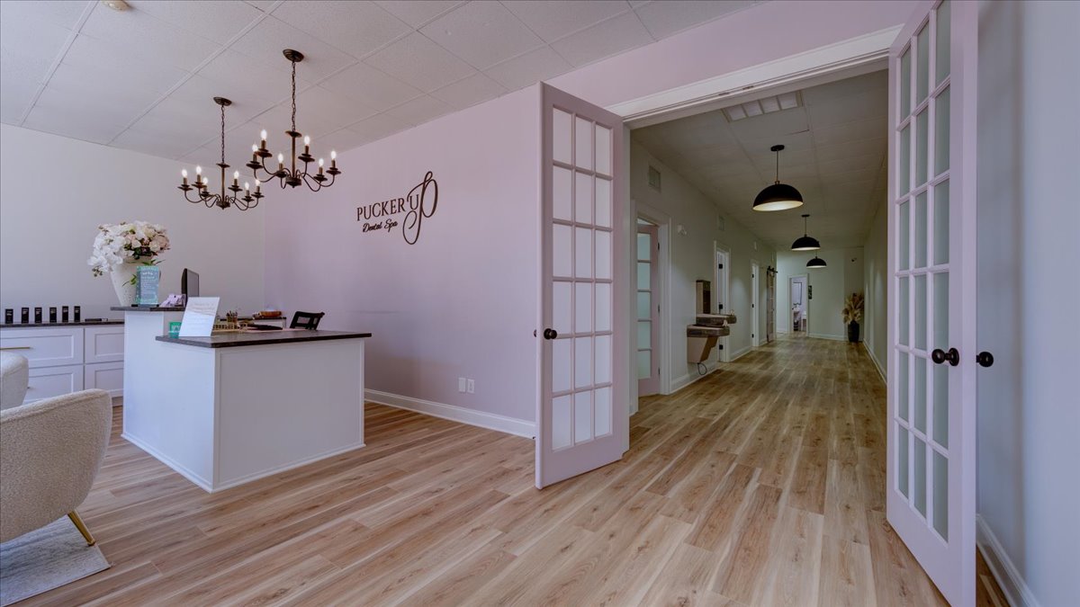 A dental office waiting room with light pink walls and chandeliers.