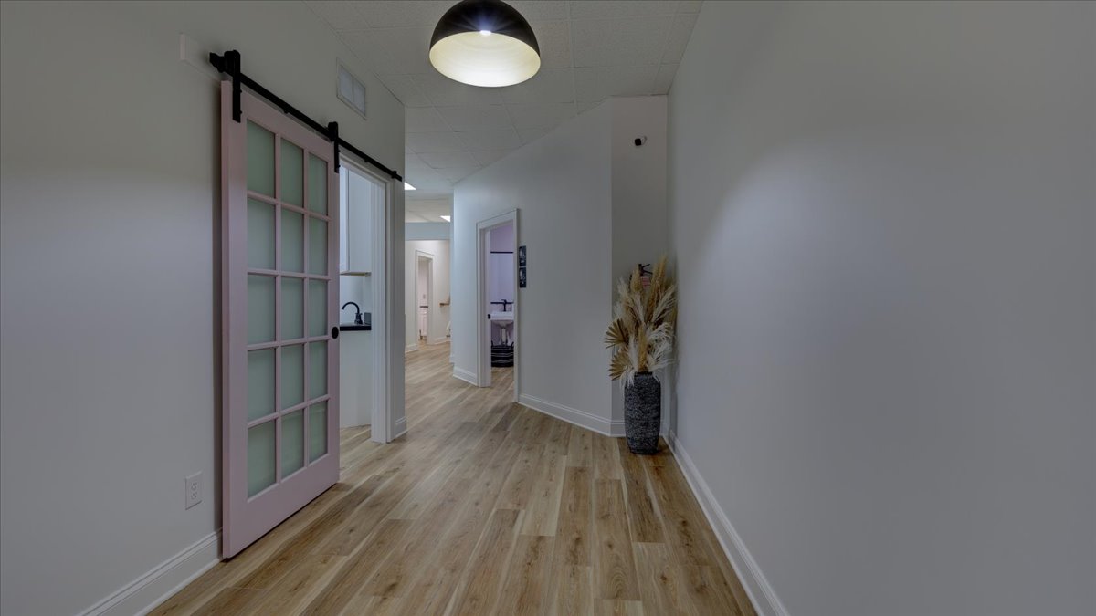 A dental office hallway with a light pink sliding barn door.