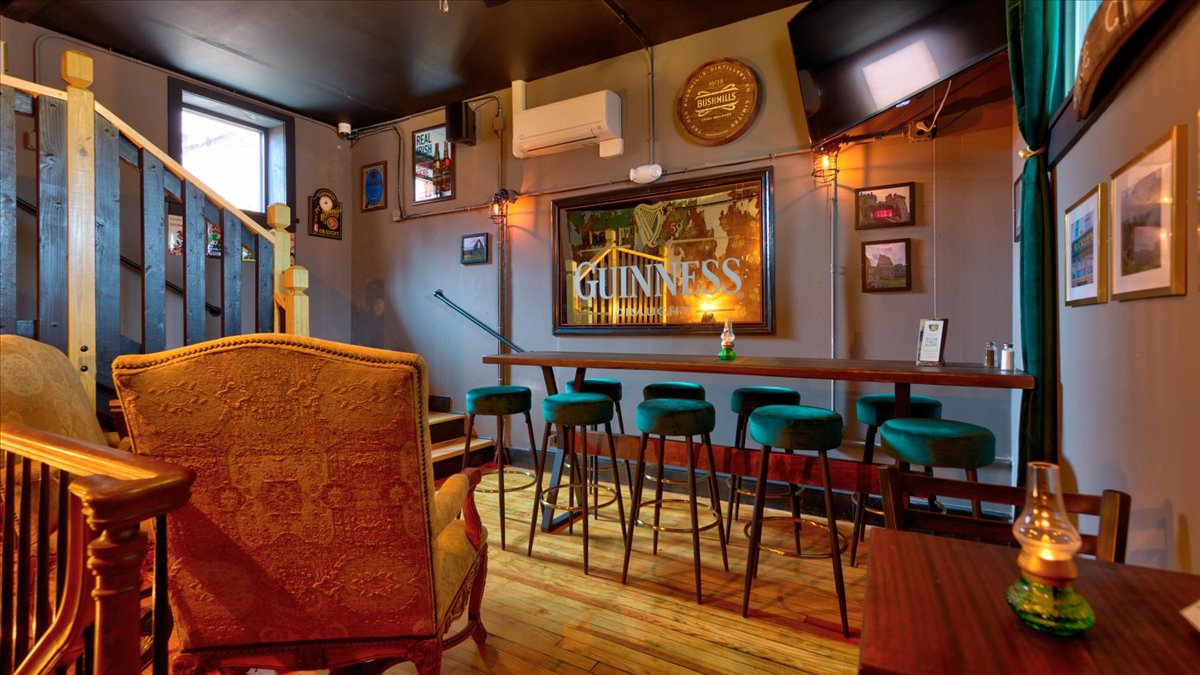A row of green velvet stools at a bar top.
