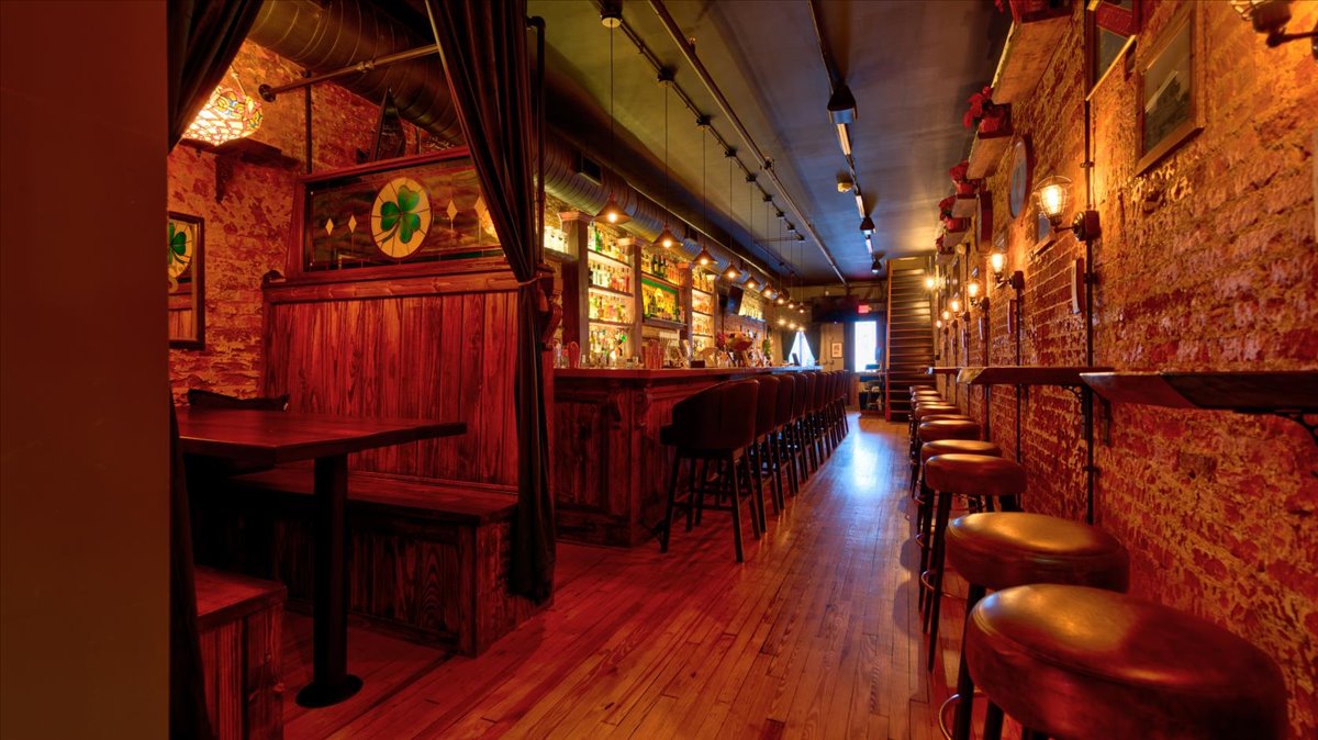 A wooden bar with stained glass, nice lighting and liquor.