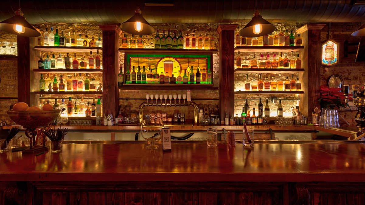 A wooden bar with stained glass, nice lighting and liquor.