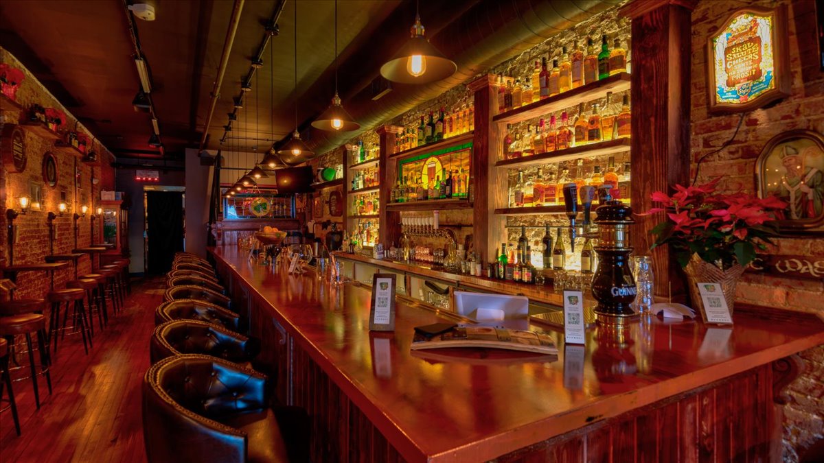 A wooden bar with stained glass, nice lighting and liquor.