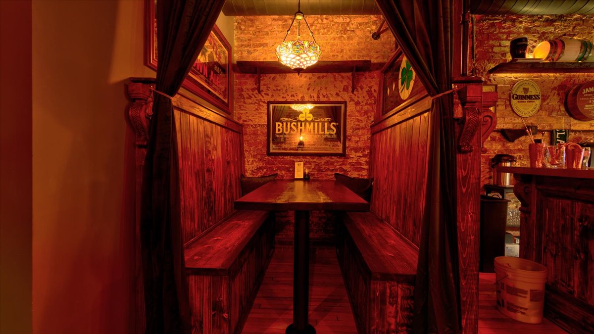 A wooden booth in a dimly lit bar with a brick wall.
