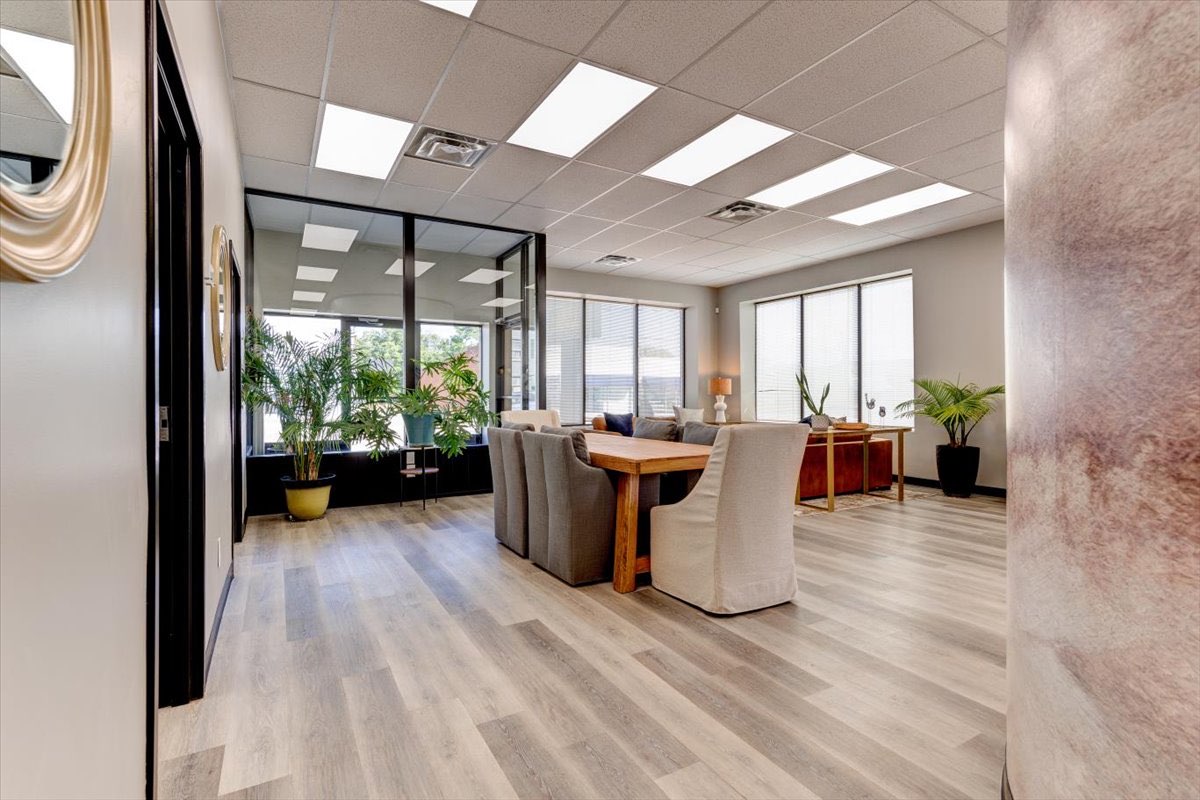 A modern office waiting room with plants and a table.