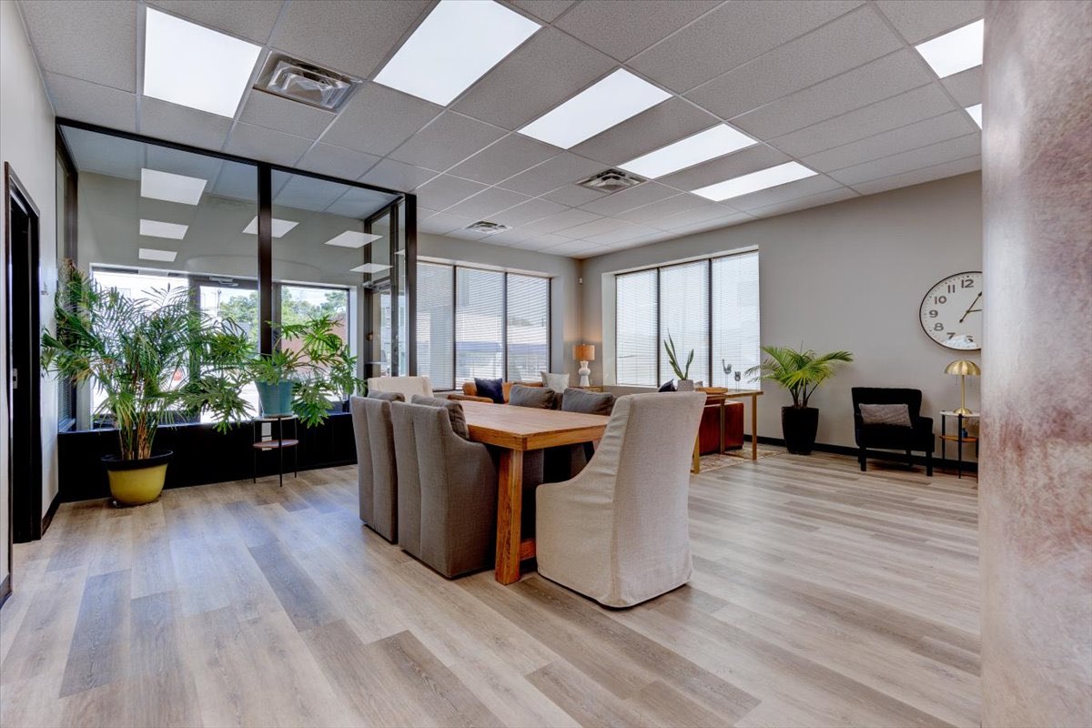 A modern office waiting room with plants and a table.