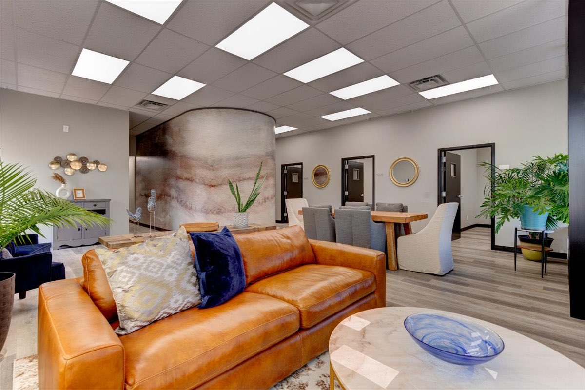 A modern office waiting room with a orange leather couch.