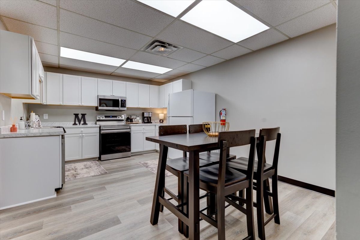 An office kitchenette with white cabinets and a small table and chairs.