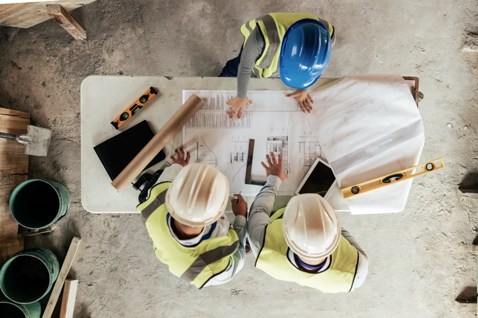 A team of construction workers reviewing a set of building plans on a table.
